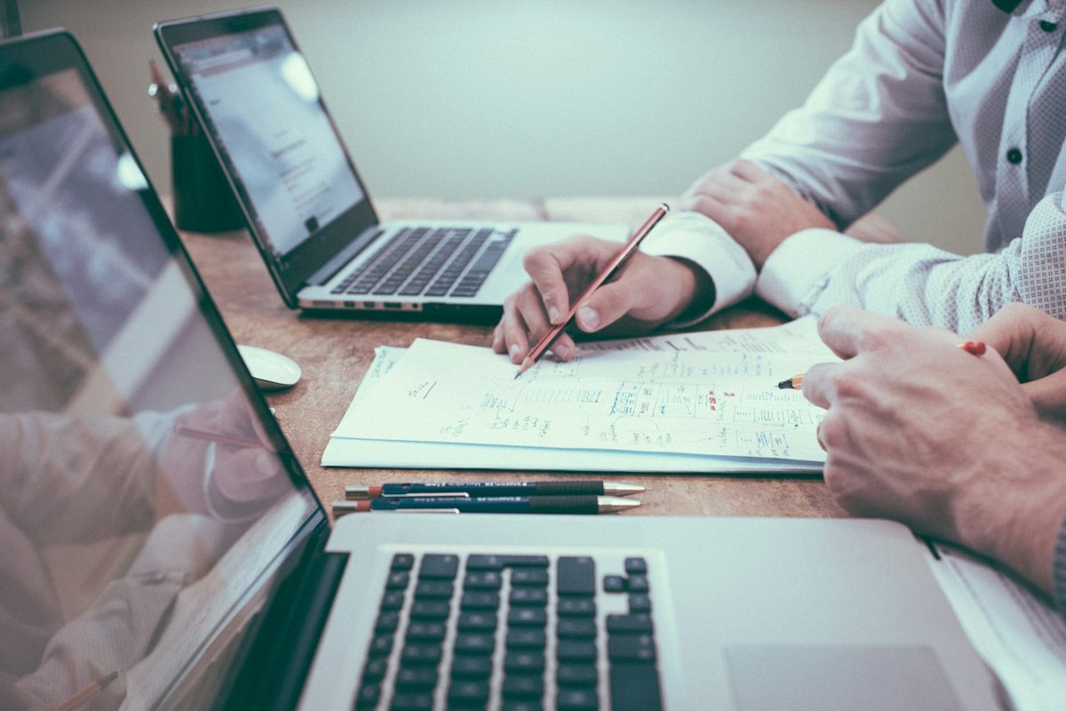 Person at a desk with laptop, notebook, and charts while reviewing a refinance or budget plan